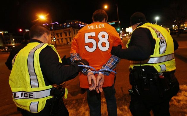 Denverská policie odvádí jednoho z fanoušků, který to přehnal se slavením triumfu Bronchos ve finále ligy amerického fotbalu NFL.