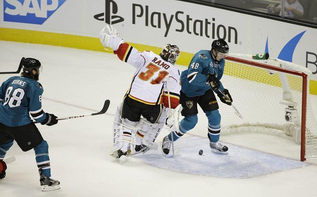 Žralok Burns prostřelil gólmana Calgary Rama. Brankovištěm projíždí český útočník Tomáš Hertl.