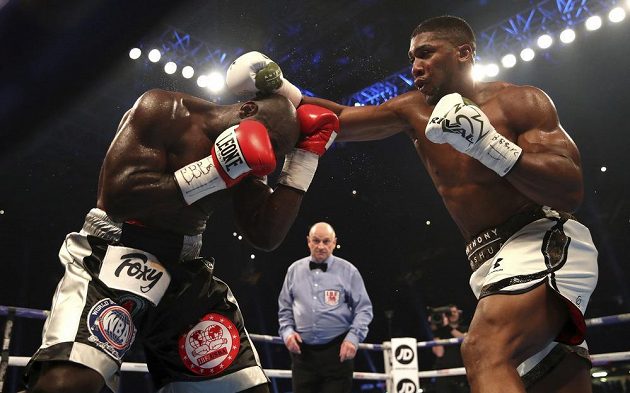 Anthony Joshua (vpravo) a Carlos Takam v boji o tři pásy organizací IBF, WBO a IBO.