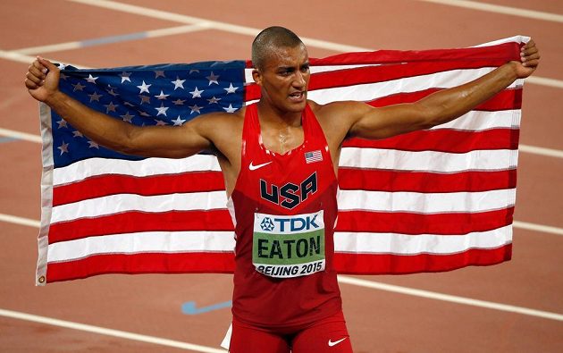 Američan Ashton Eaton slaví s vlajkou po triumfu v desetiboji na MS v Pekingu.