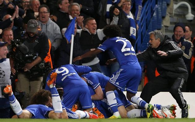 Útočník Chelsea Demba Ba v objetí spoluhráčů a kouče Joseho Mourinha poté, co vstřelil postupový gól Chelsea do semifinále Ligy mistrů.