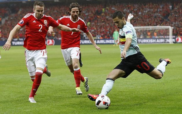 Velšané Chris Gunter a Joe Allen se snaží blokovat střílejícího belgického tvůrce hry Edena Hazarda.