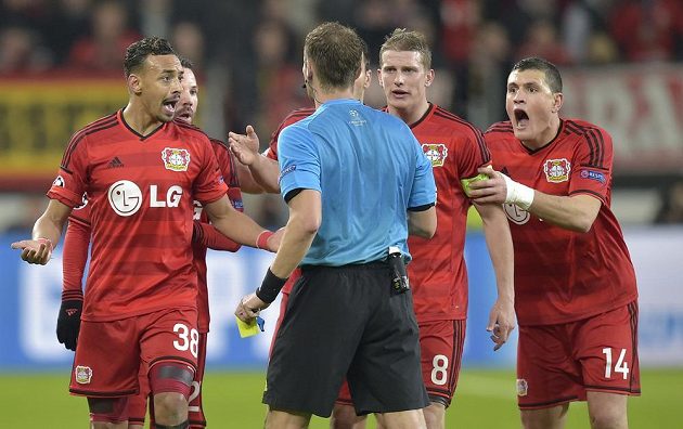 Leverkusenský Kyriakos Papadopulos (vpravo) dostává žlutou kartu od rozhodčího Pavla Královce v úvodním osmifinále Ligy mistrů.