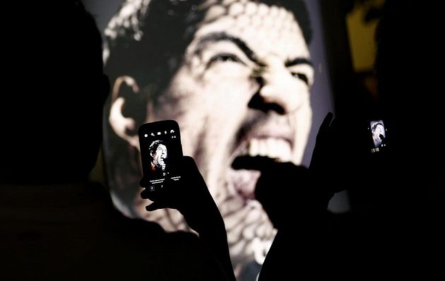 Fanoušci si na plaží Copacabana v Riu fotografují reklamní billboard, na němž Luis Suárez cení zuby.