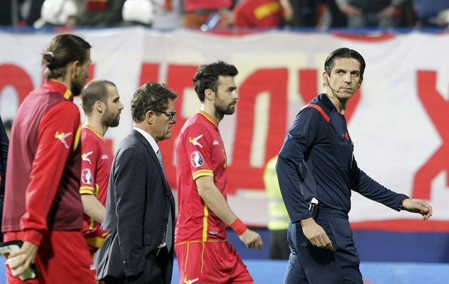 Rozhodčí Deniz Aytekin (vpravo) z Německa odvádí fotbalisty Ruska i Černé Hory ze hřiště po zranění brankáře Igora Akinfejeva. Uprostřed kouč Rusů Fabio Capello