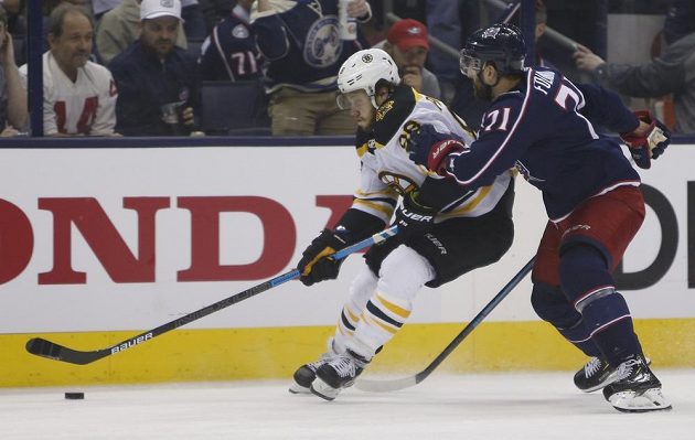 Český hokejový útočník Bostonu David Pastrňák se snaží odolat ataku Nicka Foligna z Columbusu v utkání play off NHL.
