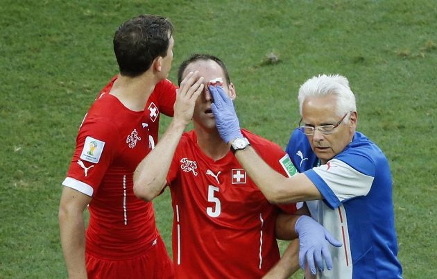 Švýcarský obránce Steve von Bergen (uprostřed) je ošetřován lékařem. Vlevo je další obránce Stephan Lichtsteiner.