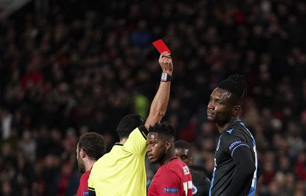 Sudí Serdar Gozubuyuk ukazuje červenou kartu Simonu Delimu z Brugg v odvetě s Manchesterem United.