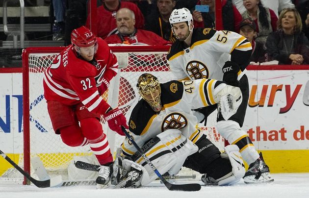 Útočník Caroliny Kris Versteeg (32) se snaží procedit puk za záda gólmana Bostonu Tuukky Raska (40) v zápase NHL. Raskovi kryje záda bek Adam McQuaid (54).