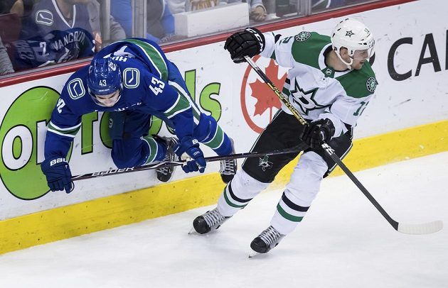 Český útočník Dallasu Radek Faksa ( v bílém) odjíždí ze souboje s Quinnem Hughesem během druhé třetiny zápasu NHL na ledě Vancouveru.