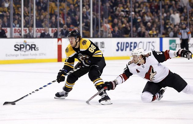 Obránce Arizony Coyotes Oliver Ekman-Larsson se snaží zastavit unikajícího Davida Pastrňáka z Bostonu v utkání NHL.