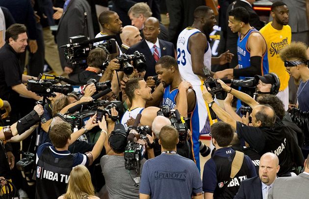 Stephen Curry z Golden State (uprostřed v bílém dresu) Kevin Durant z Oklahomy se zdraví po sedmém finále play off Západní konference NBA.