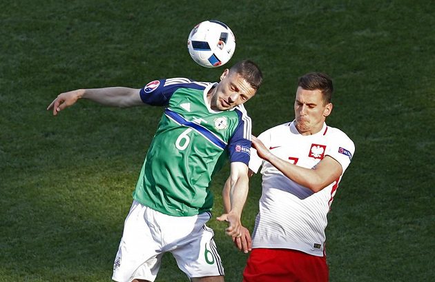 Chris Baird ze Severního Irska (vlevo) v hlavičkovém souboji s Polákem Arkadiuszem Milikem.