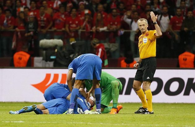 Rozhodčí Martin Atkinson volá zdravotníky poté, co se Brazilec Matheus složil na trávník.