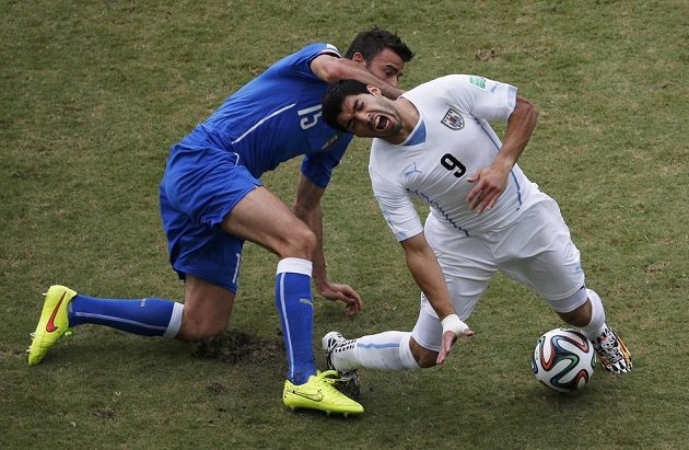 Uruguayský snajpr Luis Suárez (vpravo) padá po zákroku Itala Andrey Barzagliho.
