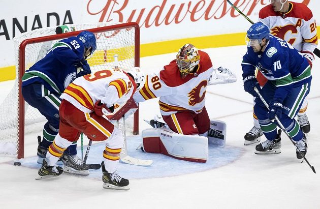 Český gólman Calgary Flames Daniel Vladař sleduje, kde skončí puk po závaru před jeho brankou v přípravném duelu s Vancouverem Canucks.