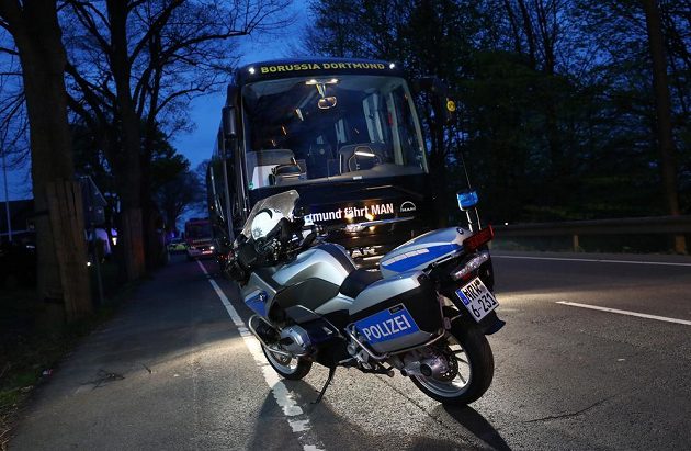 Policejní motocykl před autobusem fotbalistů Dortmundu, který poničila exploze.