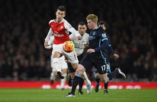 Laurent Koscielny (vlevo) z Arsenalu odkopává míč před Kevinem De Bruynem z Manchesteru City.