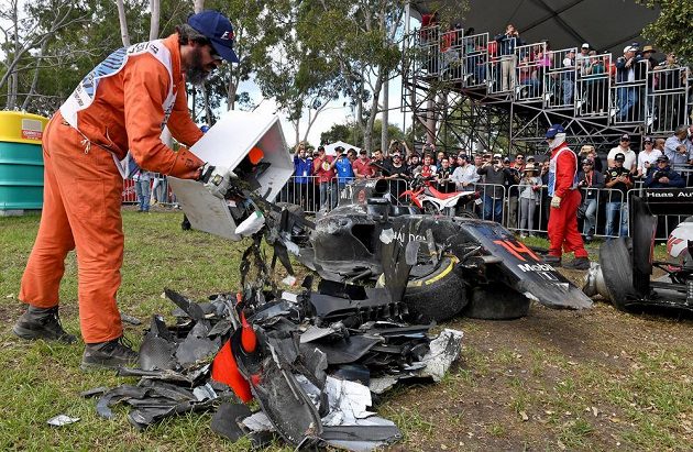 Jeden z pořadatelů hází na jednu hromadu kusy z Alonsova monopostu při Velké ceně Austrálie.