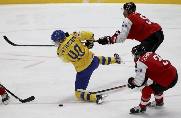 Švédský hokejista Elias Pettersson padá po ataku Rakušana Thomase Raffla v utkání mistrovství světa. Vše sleduje další Rakušan Peter Schneider.