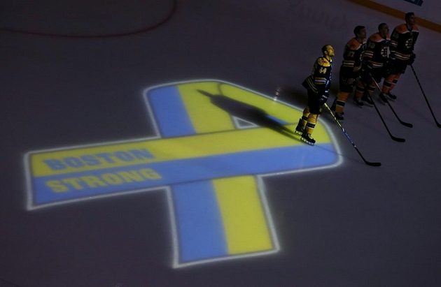 Bostonští hokejisté v čele s Dennisem Seidenbergem (44) při ceremoniálu k uctění obětí teroristických útoků při bostonském maratonu před duelem s Buffalem.