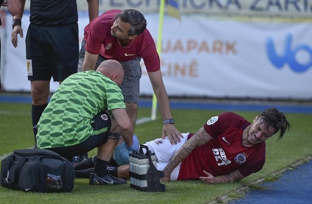 Masér Sparty Kamil Maixner (v zeleném triku) a lékař týmu Miroslav Sinkule (uprostřed) ošetřují zraněného útočníka Sparty Václava Kadlece.