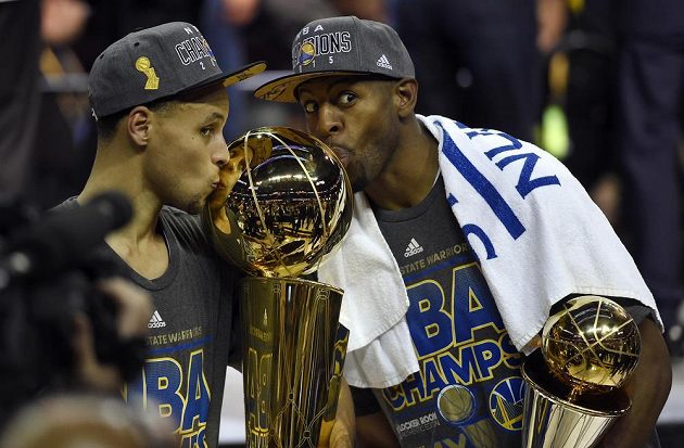 Hvězda Golden State Stephen Curry (vlevo) a nejužitečnější hráč finálových soubojů Andre Iguodala s trofejí.
