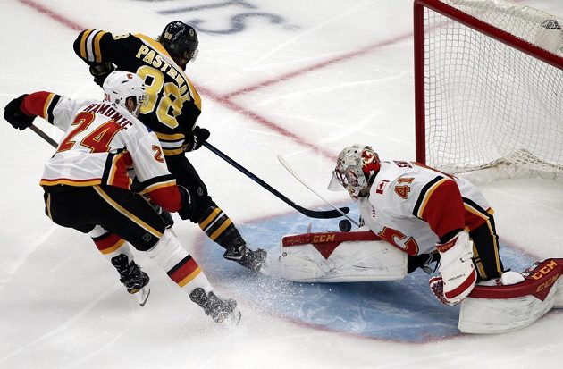 Český útočník Bostonu David Pastrňák zkouší překonat brankáře Calgary Mikea Smithe (41) v utkání NHL.