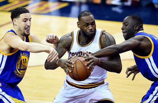 Hvězda Clevelandu LeBron James v sevření bránících hráčů Golden State Klaye Thompsona (vlevo) a Draymonda Greena.