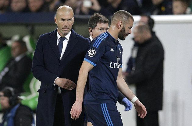 Fotbalista Realu Madrid Karim Benzema vedle kouče Zinedina Zidana opouští hřiště na stadiónu Wolfsburgu po zranění.