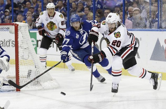 Brandon Saad (vpravo) z Chicaga přihrává puk, obránce Lightning Victor Hedman už zasáhnout nestačil.