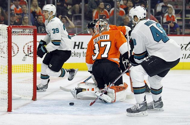 Puk už míří ven z branky Philadelphie, vlevo autor gólu San Jose Logan Couture (39), vpravo Tomáš Hertl, mezi nimi brankář Flyers Brian Elliott.