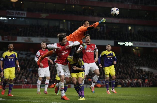 Brankář Swansea Michel Vorm vyráží míč nad Neilem Taylorem (č. 3) a Tomášem Rosickým z Arsenalu.