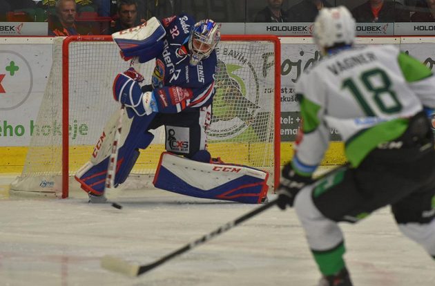 Brankář Vítkovic Patrik Bartošák odpaluje puk před karlovarským obráncem Lukášem Vágnerem.