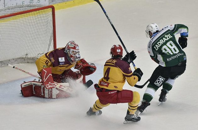 Matěj Zadražil z Karlových Varů překonává jihlavského brankáře Miroslava Svobodu v utkání 11. kola baráže o hokejovou extraligu. Zákrok jihlavského obránce Petra Šidlíka přišel pozdě.