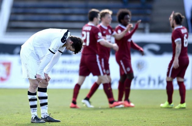 Zklamaný hradecký obránce Jakub Chleboun po inkasovaném gólu od Sparty, jejíž hráči oslavují.