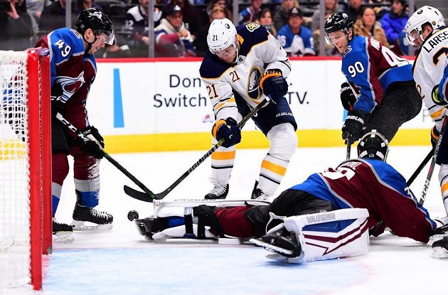 Kyle Okposo (21) z Buffala se pokouší dostat puk do sítě Colorada v utkání NHL. Na ledě je gólman Pavel Francouz.