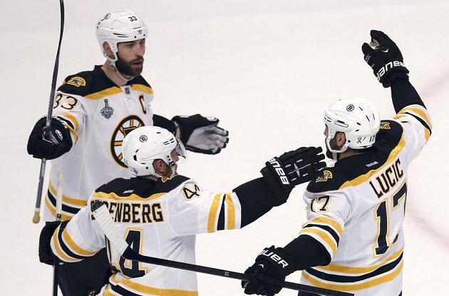 Milan Lucic (vpravo) oslavuje se spoluhráči z Bostonu Chárou (vlevo) a Seidenbergem svůj gól na 1:0 proti Chicagu.
