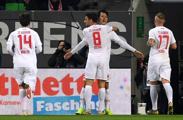 Fotbalista Augsburgu Ji Dong-won slaví se spoluhráči gól v síti slavného Bayernu Mnichov. Gratulovat spěchá i český fotbalista Jan Morávek.