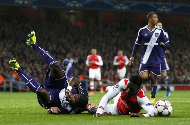 Fotbalista Arsenalu Danny Welbeck (vpravo) padá k zemi po faulu od Chancela Mbemby z Anderlechtu.