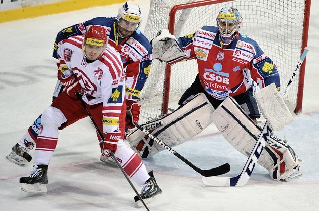 Zleva třinecký útočník Daniel Rákos, obránce Pardubic Jiří Vašíček a brankář Július Hudáček.