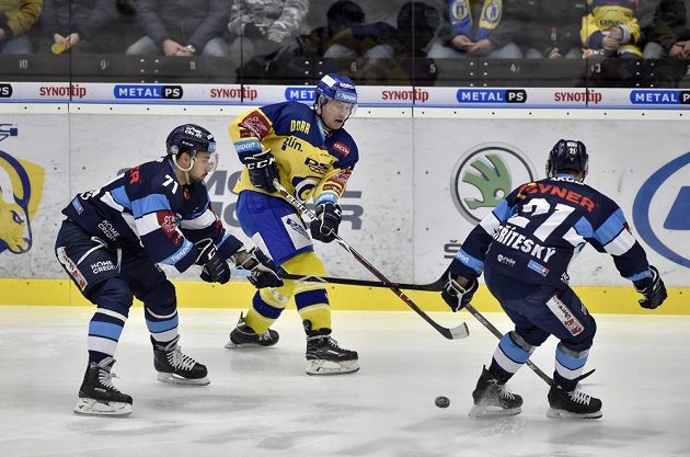 Zlínský hokejista Pavel Kubiš rozehrává puk přes bránící liberecké hráče Jakuba Valského a Matěje Stříteského v utkání extraligy.