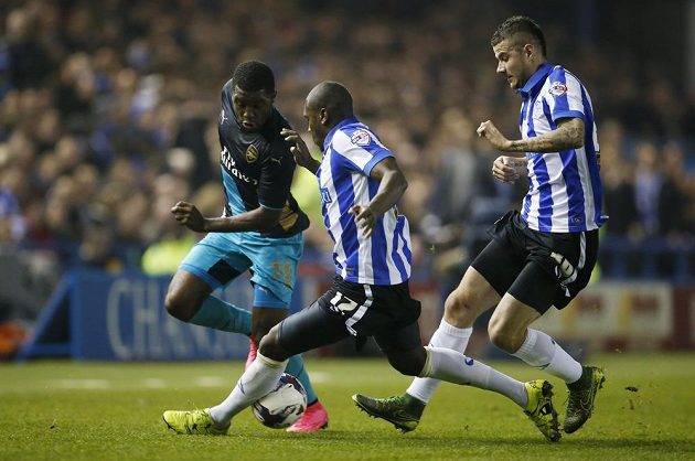 Joel Campbell z Arsenalu v souboji s dvojicí fotbalistů Sheffieldu Wednesday - Jeremym Helanem a Danielem Pudilem (vpravo).