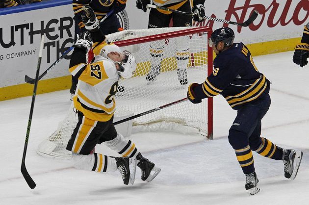 Kapitán Pittsburghu Sidney Crosby padá k ledu po zákroku Evandera Kanea z Buffala hokejkou do obličeje.