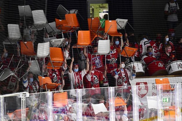 Fanoušci Pardubic drží nad hlavami židle, které jim klub v rámci protikoronavirových opatření připravil do sektoru na stání.