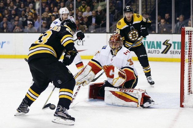 Hvězda Bostonu Brad Marchand (63) zkouší překonat českého brankáře Calgary Flames Davida Ritticha v utkání NHL.