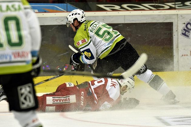 Slávistický útočník Milan Mikulík (ležící) a karlovarský obránce Jekabs Redlihs (vpravo) v zápase 6. kola baráže o extraligu.