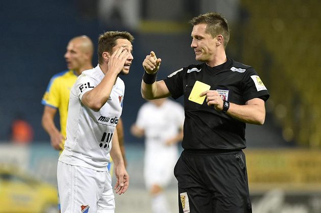 Střelec prvního gólu Baníku Ostrava Adam Jánoš (vlevo) dostává žlutou kartu během utkání v Teplicích.