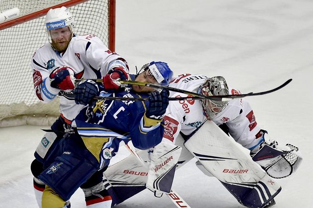 Drsný souboj před brankou Chomutova v baráži o extraligu. Kladenský Jakub Strnad čelí ataku David Šticha z Chomutova. Připravený zasáhnout je brankář Chomutova Justin Peters.