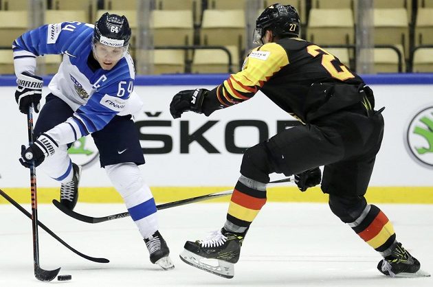 Finský šikula Mikael Granlund (vlevo) kouzlí s pukem, zastavit se ho snaží Sebastian Uvíra z Německa. 